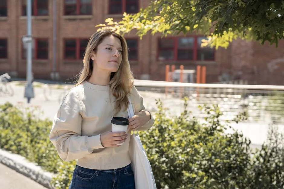 A person holds a cup of coffee while walking through an outdoor market.