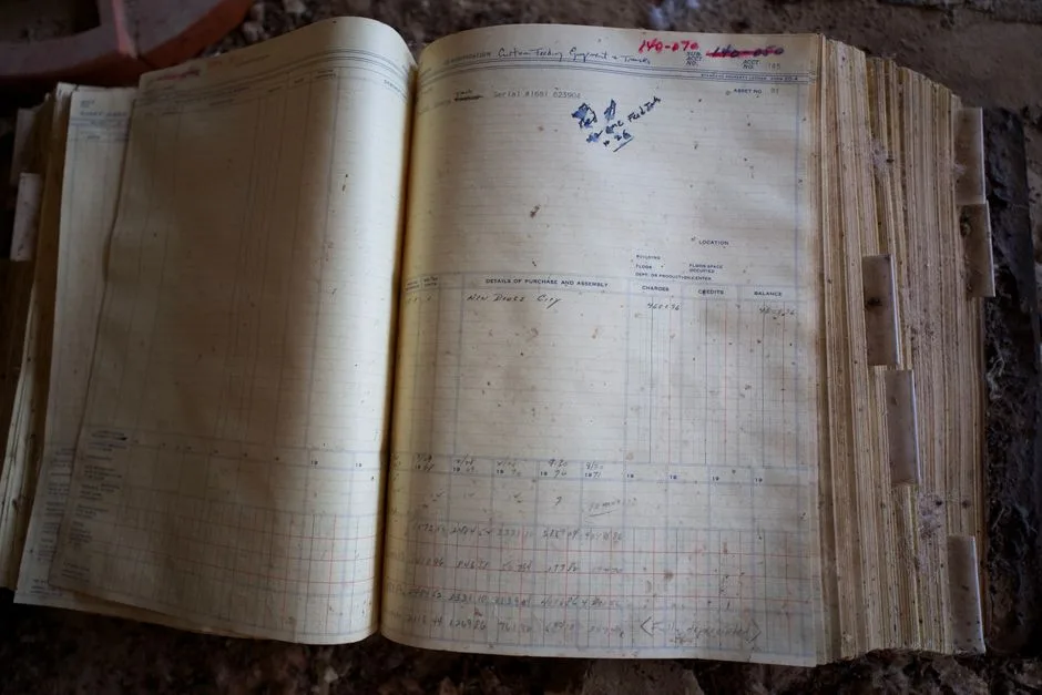 An old ledger with cursive handwriting lies open on a wooden desk.