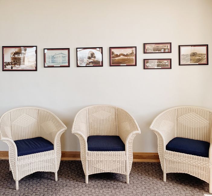A comfortable armchair sits next to a window in a quiet, book-lined waiting room.