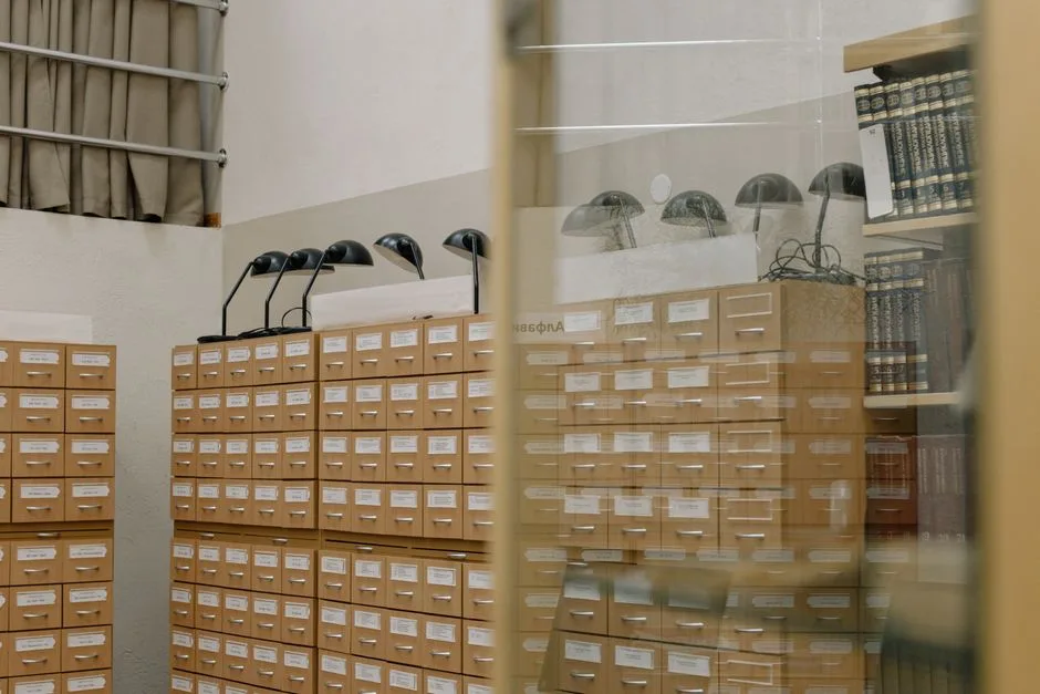 Close-up on the small wooden drawers and brass pulls of a vintage card catalog.